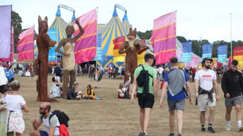 Getty Images A group of people walking around the Electric Picnic site in 2022 with large wicker fox structures and tents and flags around them