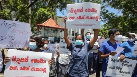 EPA Members of the Government Medical Officers" Association (GMOA) hold placards during a protest demanding immediate solutions to the shortage of medicines and medical equipment, in Colombo, Sri Lanka, 06 April 2022.