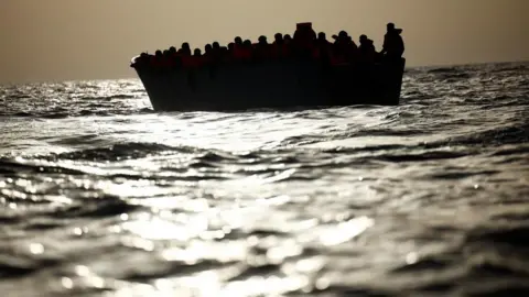 Reuters Migrants (seen in silhouette) wait in a boat during a search and rescue operation in the Mediterranean.