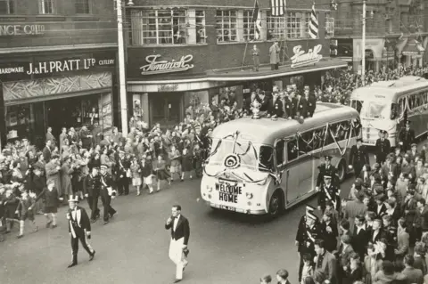 Fenwick 1955 FA cup parade bus passes by crowds in front of Fenwick's