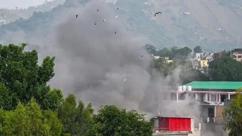 AFP via Getty Images Smoke billows after an artillery shell landed in the main town of Poonch district in India's Jammu region on May 7, 2025. At least eight Indians were killed and 29 others wounded Wednesday in the town of Poonch in Kashmir, close to the de facto border with Pakistan, a local Indian government official said. (Photo by Punit PARANJPE / AFP) (Photo by PUNIT PARANJPE/AFP via Getty Images)