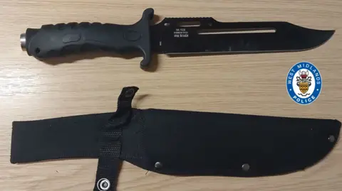 West Midlands Police A black knife on a table alongside its sheath
