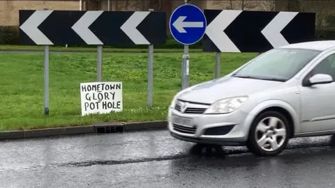 Martin Heath/BBC A small sign fixed to a roundabout direction sign