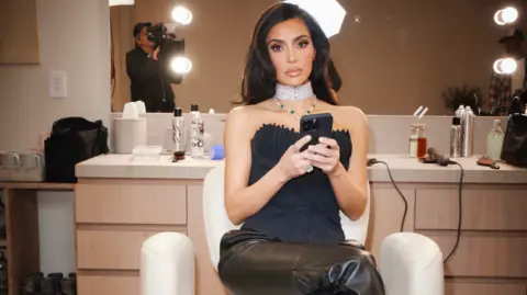 BBC/Passion Pictures/Pierre Auroux/@Pierresnaps Kim Kardashian sitting successful  a achromatic  seat  with hairsbreadth  products down  her