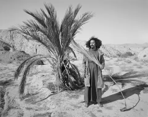 Edgar Martins A portrait of a man holing part of a plant