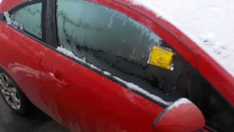 Derby City Council  Oliver Claxton's car covered in snow with a parking ticket