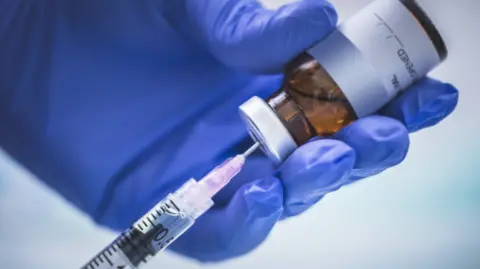 A doctor loads up a syringe