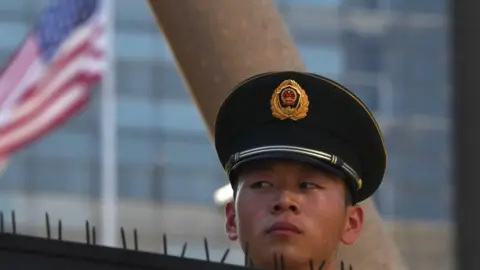 Getty Images A paramilitary policeman looks on past the US flag on the embassy compounds in Beijing