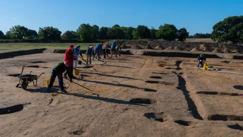 Graham Allen Fully excavated post holes on the east side of the hall, and volunteers cleaning the trench for post excavation photography