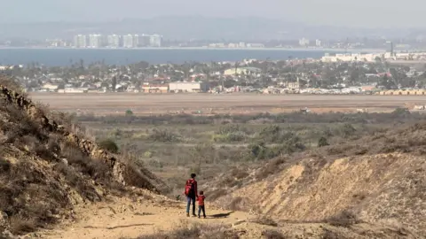 AFP/Getty A man and a child walk after crossing illegally to the US as seen from Tijuana, Mexico