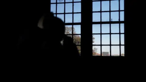  BBC A woman sitting by her window