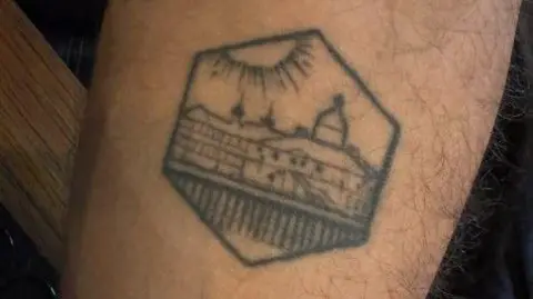 x.com/JoshBabarinde A photo of an arm tattooed with an image of Eastbourne Pier. 