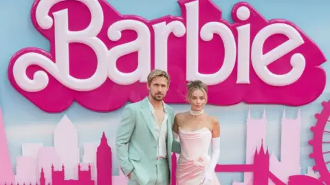 Ryan Gosling and Margot Robbie, the stars of Barbie, at one of the film's premieres in 2023. He is wearing a mint green suit an she is wearing a light pinj strapless dress.