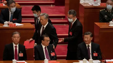 Getty Images Xi Jinping and Premier Li Keqiang look on as former President Hu Jintao is escorted out of the Communist Party Congress.