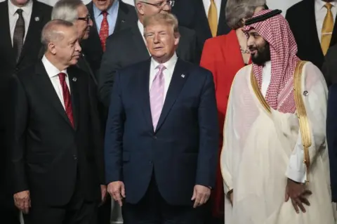 Getty Images Mr Trump flanked by the Turkish and Saudi leaders at the G20 summit in June