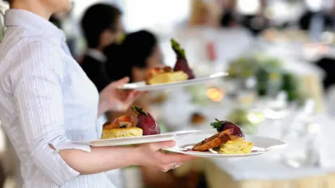 Getty Images Waitress carrying three plates.