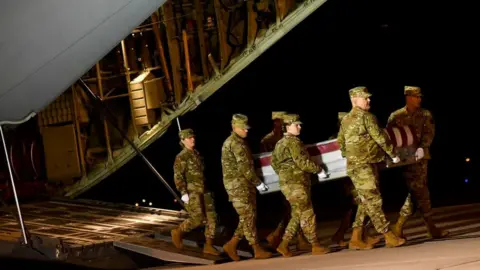 Getty Images Military personnel carry a transfer case for fallen service member Navy Ensign Joshua Watson. 8 Dec 2019