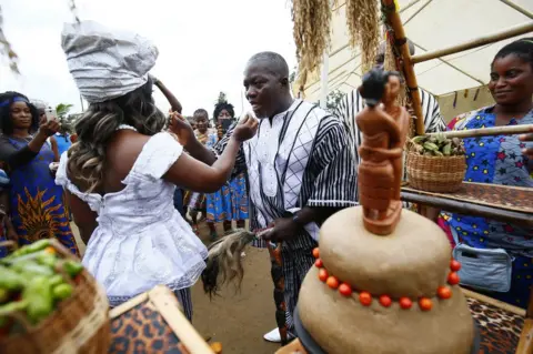 EPA The groom, Sando G. Brownell (R) and the bride, Vester Sayee (L) share wedding cake, during their traditional wedding ceremony held in the Mount Barclay Community, a suburb of Monrovia, Liberia, 30 June 2018