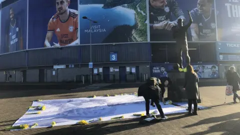 Tributes to Sala left by Cardiff fans next to statue of their FA Cup winning captain Fred Keenor