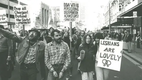Australian Lesbian and Gay Archives Marchers in the 1978 Mardi Gras and Gay Solidarity Group protests hold placards including "lesbians are lovely" and "down with all persecution and discrimination against gays!"