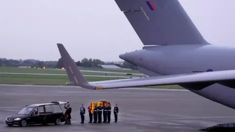 The Queen's coffin is carried from the military plane that flew it to RAF Northolt