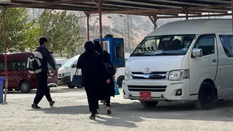 BBC People walk at a bus station in Penjwen, an Iraqi town close to the crossing post on the border with Iran