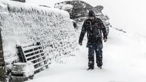 PA A man walks in snowy conditions at the Tan Hill Inn in North Yorkshire