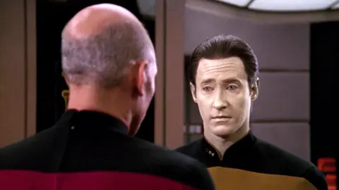 A picture of Star Trek's Capt Jean-Luc Picard speaking with android character Data