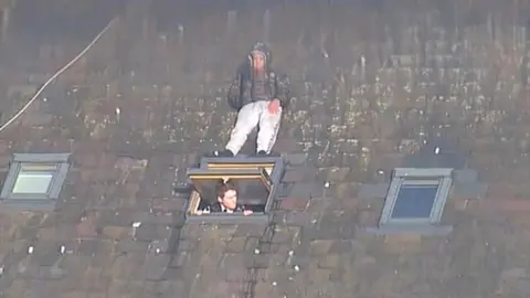 He's behind you - man hides from police on roof