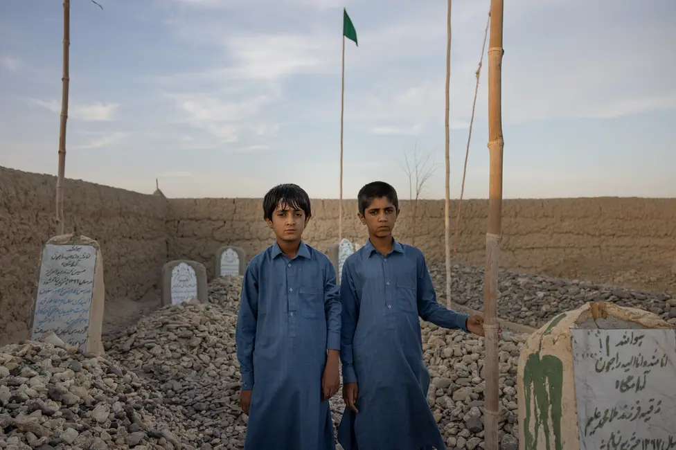 BBC Bilal and Imran Uzbakzai by their mother's grave. They were too young when she died to remember her now. Image: Julian Busch/BBC