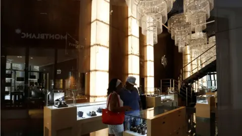 Reuters people checking out the goods at a Montblanc store, under chandaliers