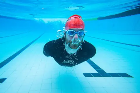 PA Media A swimmer glides underwater