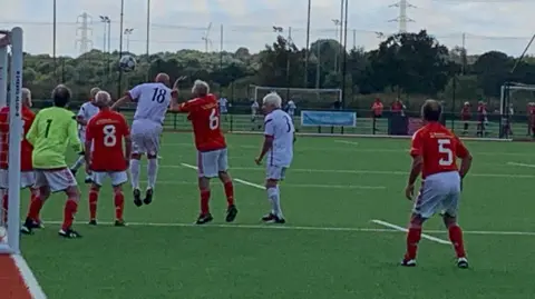 A Wales player goes in for a header during the over-75s final against England