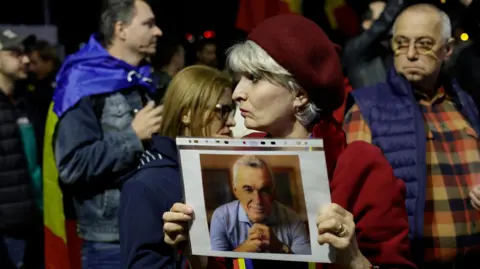 A supporter woman holds a portrait of Calin Georgescu