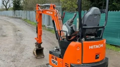 An orange digger on a dirt track. There is no driver in it