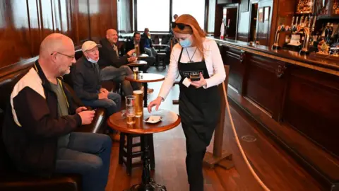 Getty Images A waitress wears a mask as she works in the pub The Grill in Union Street