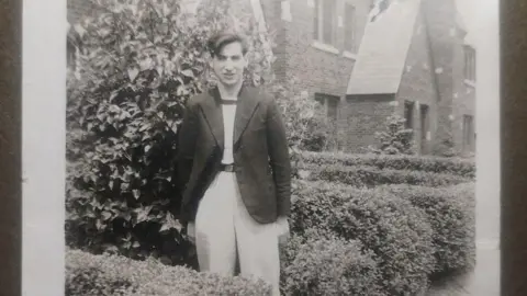 Manchester Jewish Museum/the Prager family Young man in a blazer stands in a garden with a house behind him