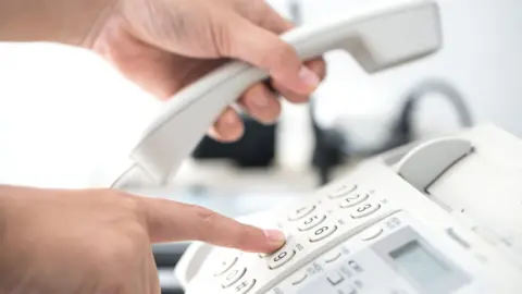 Getty Images A person reaching for a phone handset