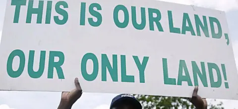 Getty Images Man holding a sign saying 'this is our land, our only land'
