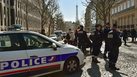 AFP French police stand near a police car outside the IMF offices in Paris, with Eiffel tower in background, on March 16 2017