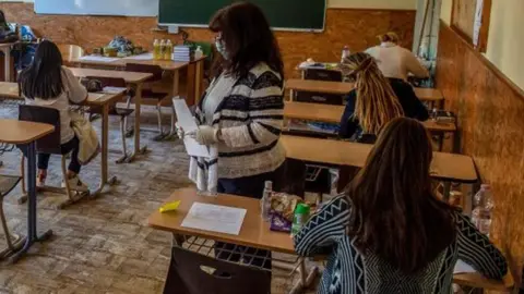 Getty Images A teacher hands out papers at Szerb Antal Grammar Schools in Budapest, Hungary, 04 May 2020