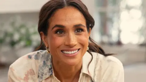 Image shows Meghan, the Duchess of Sussex, smiling at the camera 