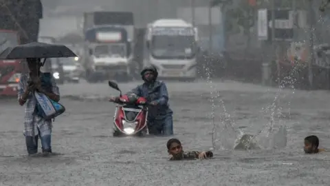 Getty Images A man pushes a motorbike on a flooded street after heavy rain showers at Santacruz Chembur Link Road, on July 2, 2019 in Mumbai, India.