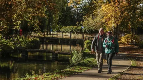 PA Media Two people walking near a river