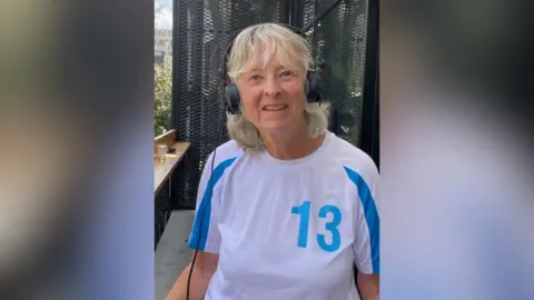 Julia Brunton A woman wearing a blue and white shirt and black headphones.