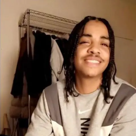 Metropolitan Police handout Image of Rico Andrews, who has shoulder length dark hair, wearing a grey tracksuit