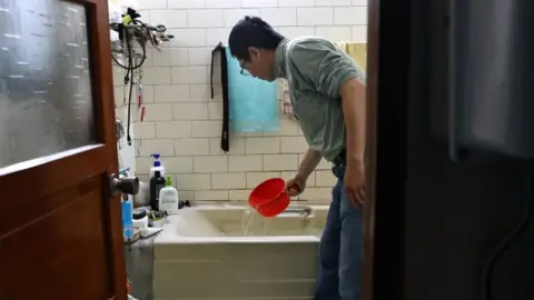 Reuters A man scoops water from a bathtub, where he stores water amid water rationing during an island-wide drought, in Hsinchu, Taiwan March 12, 2021.