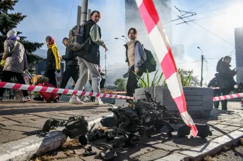 Reuters People look at the remains of an explosive drone used in a Russian attack in Kiev, Ukraine, on 17 October 2022