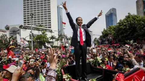 Getty Images Indonesian President Joko Widodo waves to the crowd while on his journey to the Presidential Palace by carriage during the ceremonial parade on 20 October 2014 in Jakarta, Indonesia.