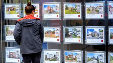 Young woman looking in an estate agent window